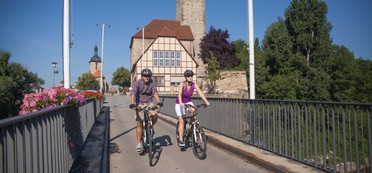 Zwei Radler auf der Brücke vor der Rathausburg
