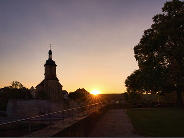 25.08.2022 - Ulrich Seidel - Regiswindiskirche mit Rathauslinde bei Sonnenuntergang als Silhoutte