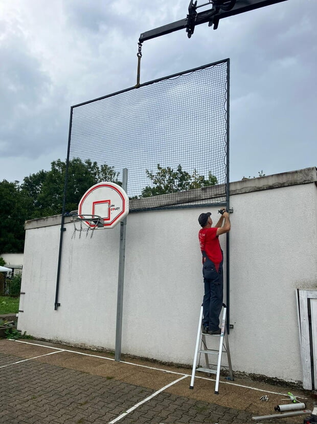 Unser Bauhofmitarbeiter, Herr Frick, installiert das Ballfangnetz