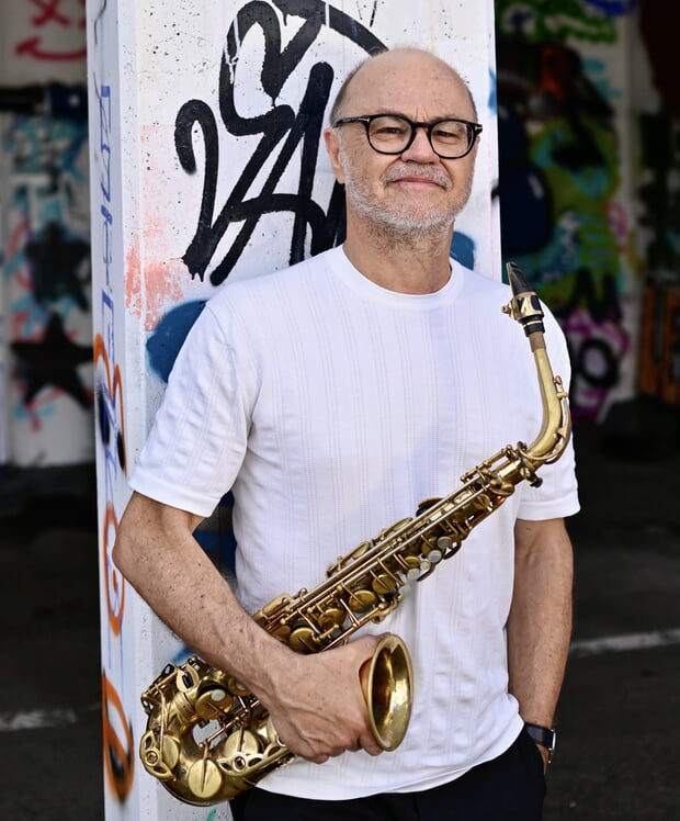 Klaus Graf mit Saxophon vor dem LaJazzO-Logo