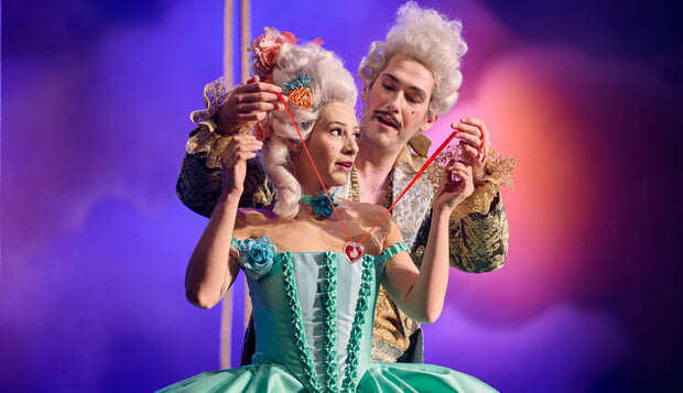 Szenenfoto aus "Così fan tutte" des Theaters Pforzheim (Ein Mann hängt einer Frau eine Kette um)