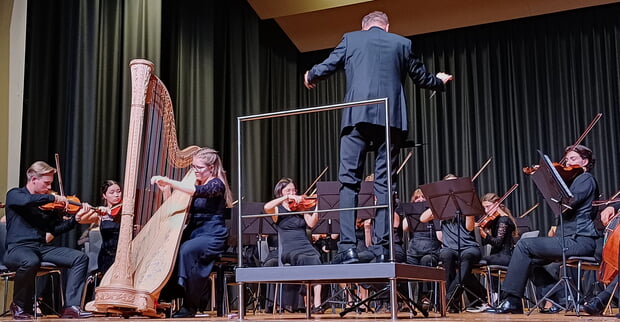 "Strings meet harp" war das perfekt gewählte Motto des Jubiläumskonzerts des Jungen Kammerorchesters Tauber-Franken in der Lauffener Stadthalle (Abbildung: Orchester auf Bühne: Harfenistin links, Dirigent in der Mitte, Streicher rechts.