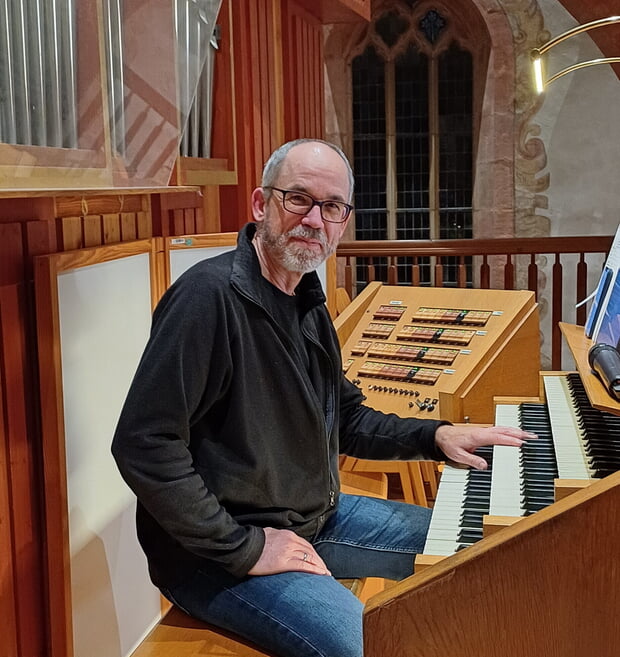Michael Schütz an der Orgel der Regiswindiskirche: Mann sitzt vor einer Orgel mit mehreren Tastaturen und Registern