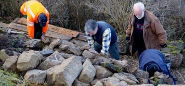 Vier Männer arbeiten an einem Haufen großer Sandsteine