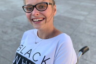 Anna Mühlhause sitz lachend im Rollstuhl , auf ihrem T-Shirt steht Black White