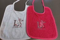 Das neue Willkommensgeschenk für Neugeborene: Ein Lätzchen, bestickt mit dem Läufer-Logo der Stadt