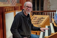 Michael Sch&uuml;tz an der Orgel der Regiswindiskirche: Mann sitzt vor einer Orgel mit mehreren Tastaturen und Registern
