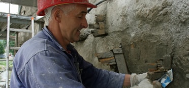 Ein Mann mit Bauhelm arbeitet an der Stadtmauer 