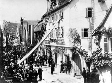 Schwarzweißfoto der Feuerwehrübung von 1913: Rettung über eine Leiter an der Hauswand