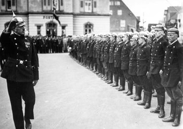 Historisches Foto: der Kommandant schreitet entlang der Aufstellung einer Feuerwehrgruppe